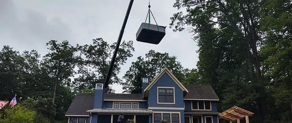 Our landscapers carefully installing a hot tub with a crane on our client's patio in Ada, MI.