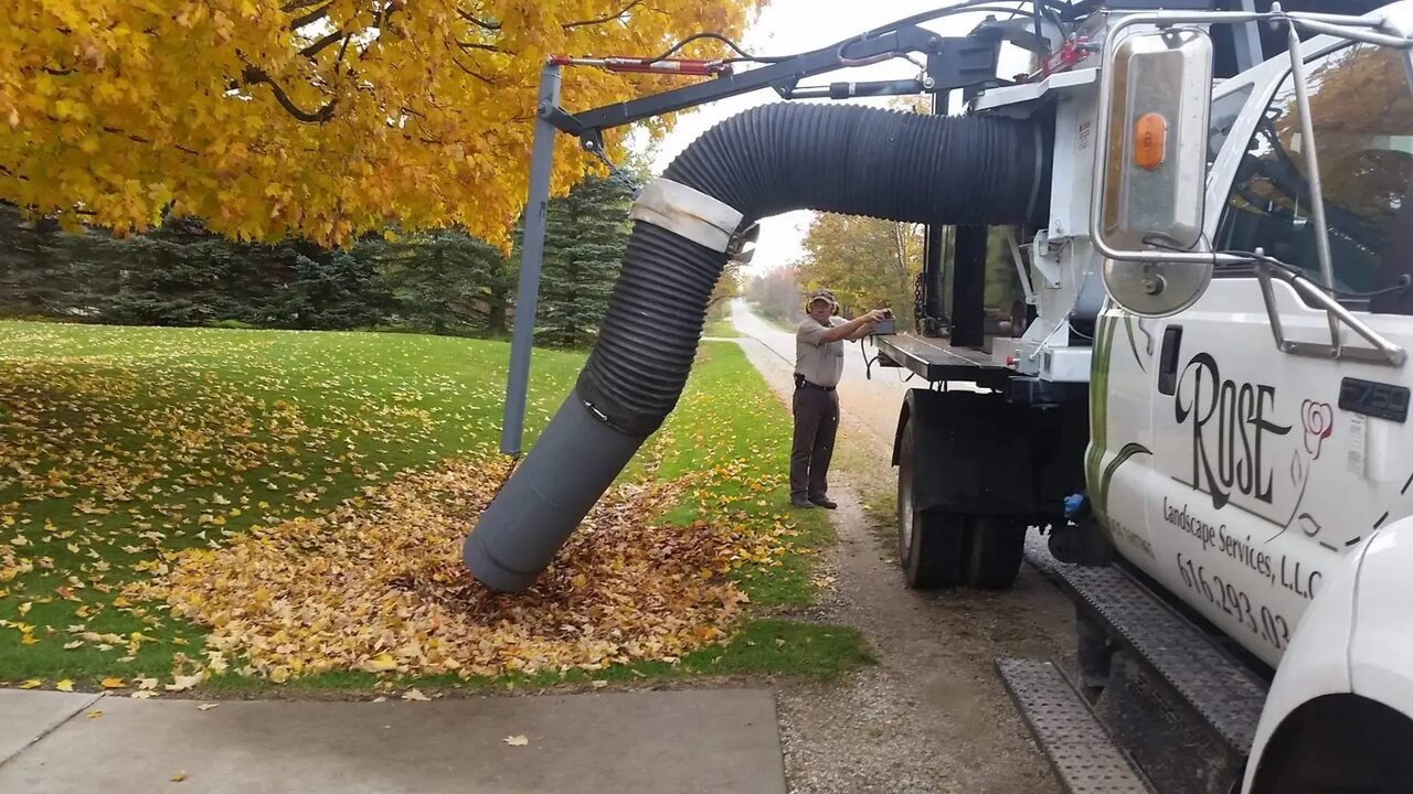 Rose’s vacuum truck collecting a roadside leaf pile under a yellow maple